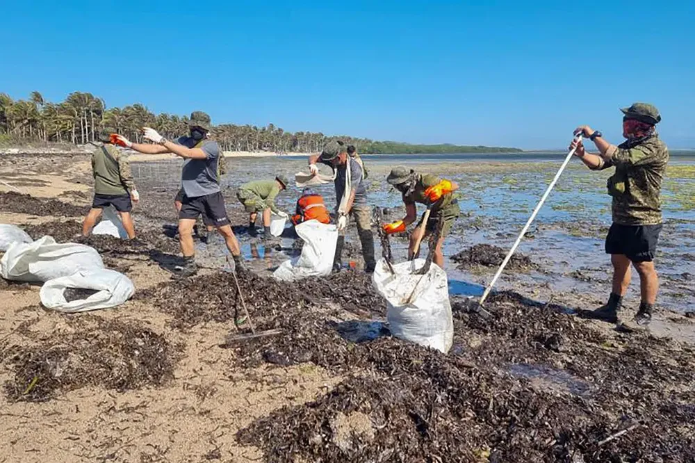 Các tình nguyện viên thu nhặt các mảnh vỡ phủ đầy dầu trên bãi biển ở thị trấn Caluya, phía nam Mindoro. Ảnh: AFP