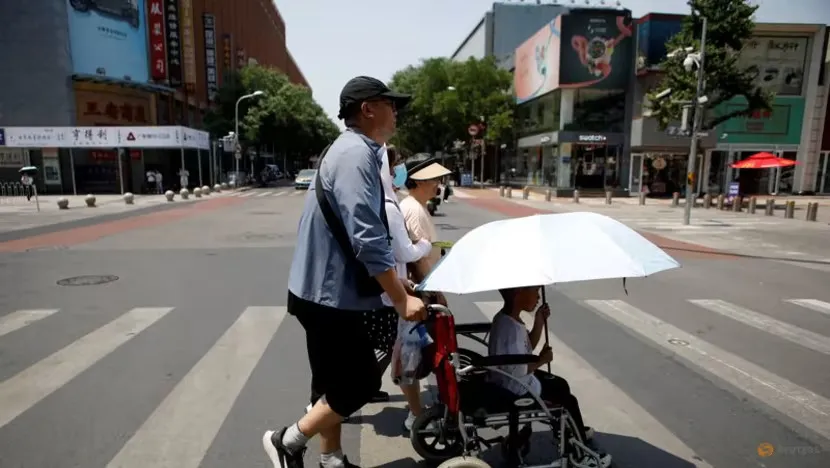 Người dân che chắn nắng nóng khi đi trên đường phố Bắc Kinh (Trung Quốc) vào ngày 16-7. Ảnh: REUTERS