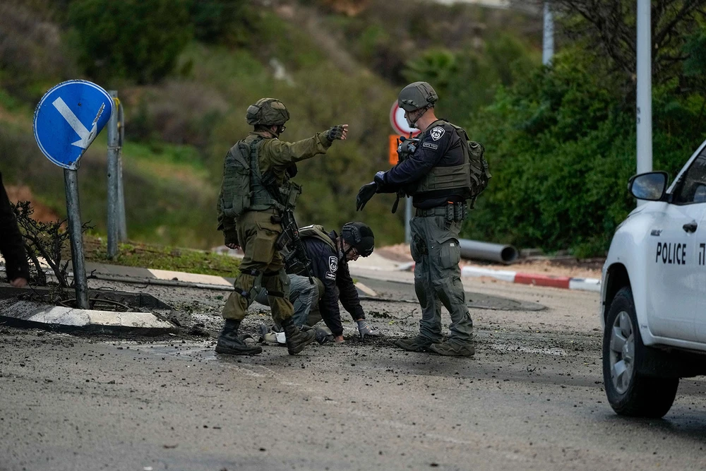 Lực lượng an ninh Israel kiểm tra một con đường ở miền bắc Israel bị trúng rocket bắn từ Lebanon ngày 11-1. Ảnh: AP Xung đột Israel-Hamas 12-1