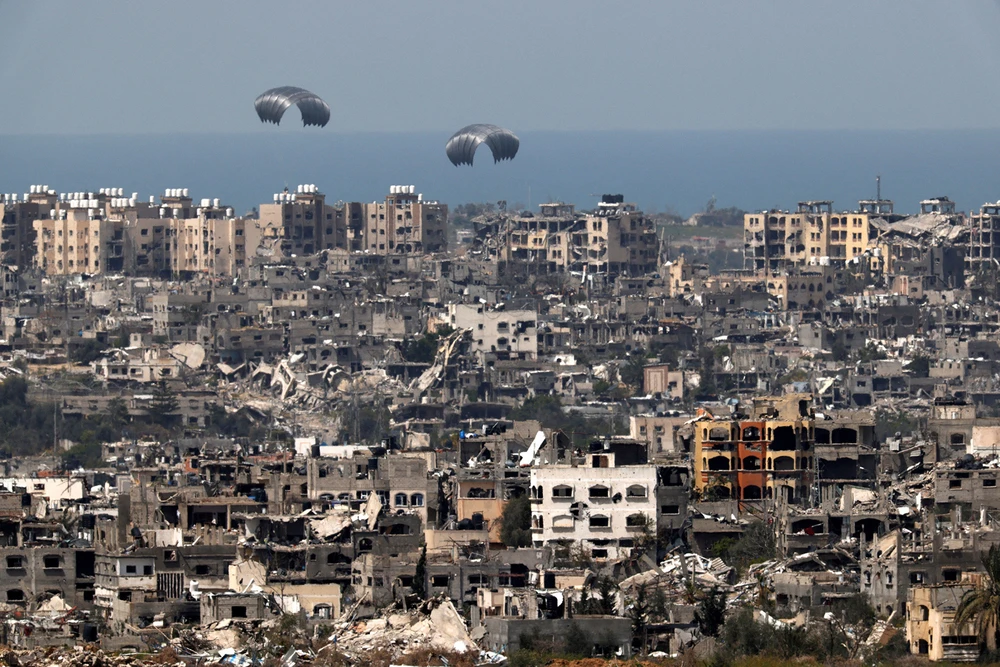 Hàng viện trợ nhân đạo được thả từ máy bay xuống Dải Gaza ngày 26-3. Ảnh: REUTERS 12 người Gaza chết thảm khi bơi ra biển vớt hàng viện trợ