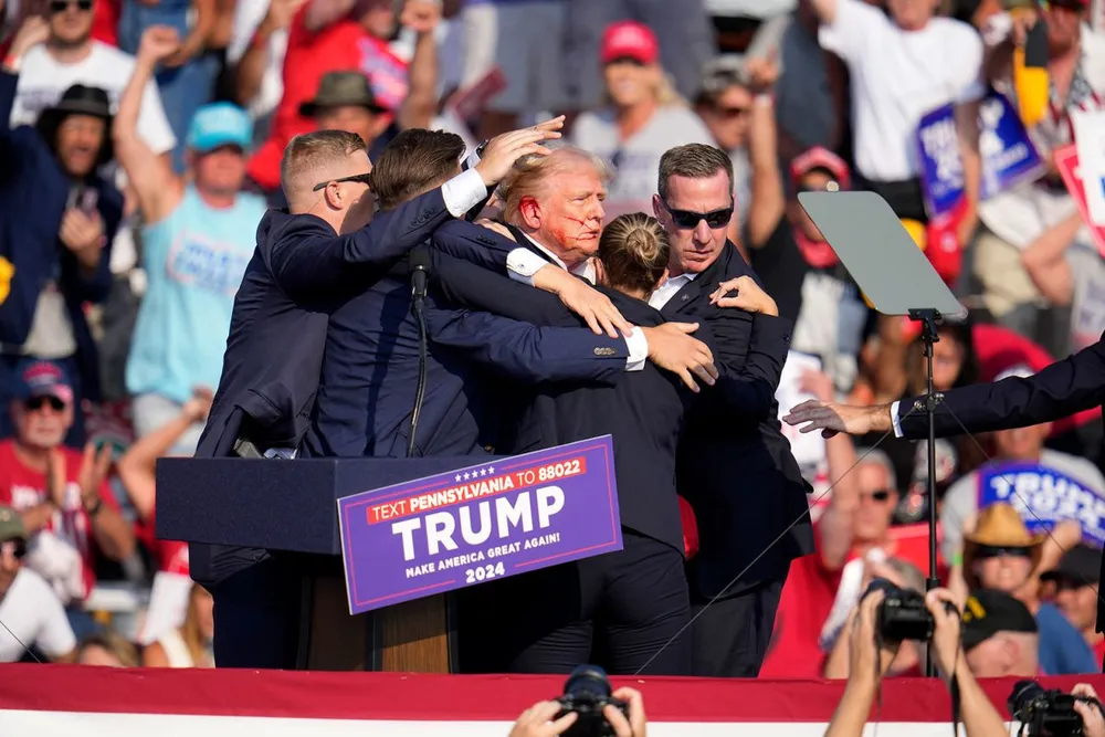 Cựu Tổng thống Donald Trump được dìu xuống sân khấu sau khi bị chảy máu ở tai tại một sự kiện vận động tranh cử ở bang Pennsylvania ngày 13-7. Ảnh: AP Nhiều chính trị gia Mỹ phẫn nộ việc ông Trump bị thương khi vận động tranh cử