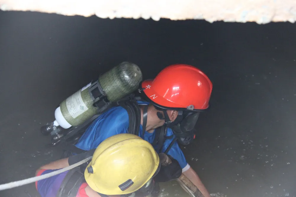 Công việc tìm kiếm nạn nhân dưới ống cống rất khó khăn - Ảnh: Bá Sơn