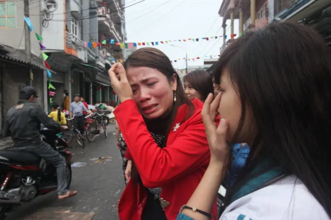 Chị Trần Thị Loan (áo đỏ) khóc nghẹn khi toàn bộ số hàng trị giá cả trăm triệu đồng bị thiêu rụi - Ảnh: Tiến Thắng