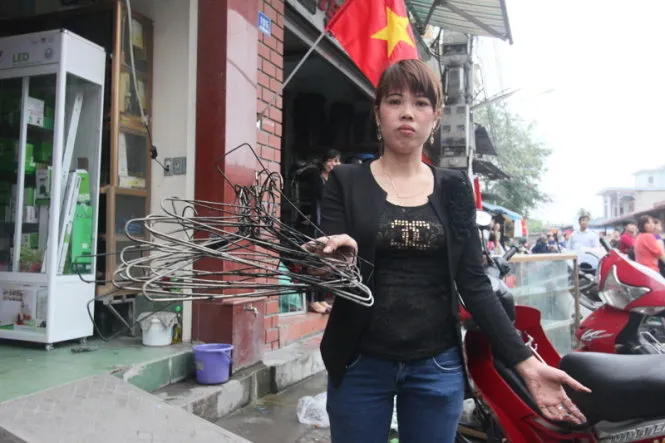 Chị Nguyễn Thị Hạnh (tiểu thương trong chợ Kinh Môn) giữ lại được vài móc quần áo còn sót lại - Ảnh: Tiến Thắng