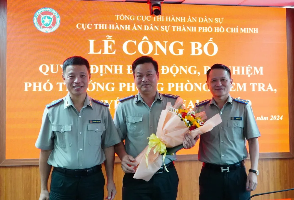 Lãnh đạo Cục THADS TP.HCM tặng hoa chúc mừng ông Phan Văn Đức (giữa) - tân Phó trưởng phòng Phòng Kiểm tra, giải quyết khiếu nại, tố cáo. Ảnh: CẨM TÚ Cục THADS TP.HCM