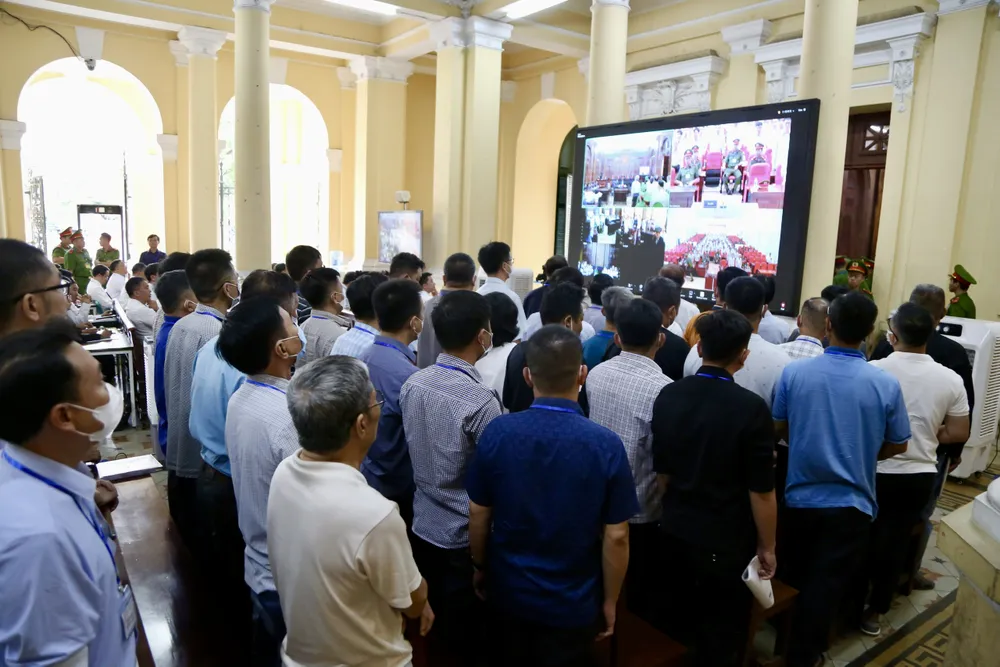 Các bị cáo trong đại án đăng kiểm theo dõi phiên xét xử qua màn hình lớn. Ảnh: HOÀNG GIANG đại án đăng kiểm các bị cáo ở sảnh lớn.jpg