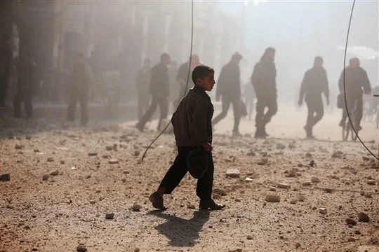 7 nước nào chiếm lĩnh vũ đài thế giới năm 2014? ảnh 4 Một cậu bé đi gần một khu vực bị tàn phá bởi trận pháo kích của lực lượng trung thành với Tổng thống Syria Bashar Assad tại Duma, Damascus hôm 22-12. Ảnh: Reuters