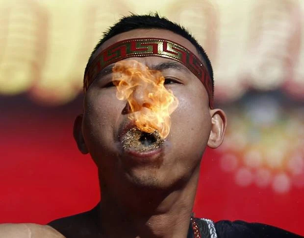 A man holds burning dry grass in his mouth while spitting a flame as he performs a feat of his strength during the opening of the temple fair for the Chinese New Year celebrations at Ditan Park, also known as the Temple of Earth, in Beijing January 30, 2014. (KIM KYUNG-HOON/REUTERS)