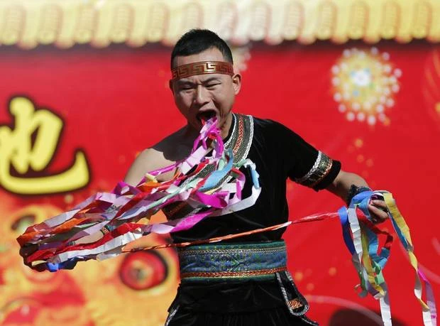 A man pulls ribbons from his mouth as he performs a feat of his strength during the opening of the temple fair for Chinese New Year celebrations at Ditan Park, also known as the Temple of Earth, in Beijing January 30, 2014. (KIM KYUNG-HOON/REUTERS)