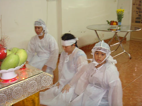 Bà Dương Thị Thảo cùng 2 con thắp hương chuẩn bị cúng cơm cho chồng, cha là ông Nguyễn Văn Chín và bút tích của ông Chín (ảnh nhỏ)