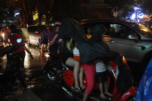 Cả gia đình vội vã mặc áo mưa ra về