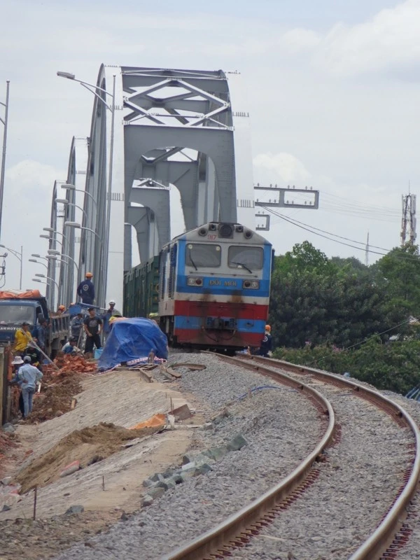(Tàu hàng qua cầu trong buổi trưa ngày 29-6 với vận tốc 5 km/giờ trong khi vách ta luy phía thượng lưu của bờ Nam chưa hoàn thiện)