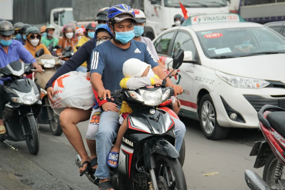 Nhiều em nhỏ cùng ba mẹ đi xe máy hàng trăm cây số về quê nghỉ lễ.