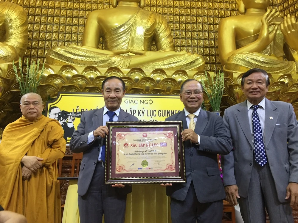 Đại diện Tổ chức kỷ lục Việt Nam (Vietkings) trao kỷ lục thứ hai cho nhiếp ảnh gia Võ Văn Tường - Ảnh: Q.T
