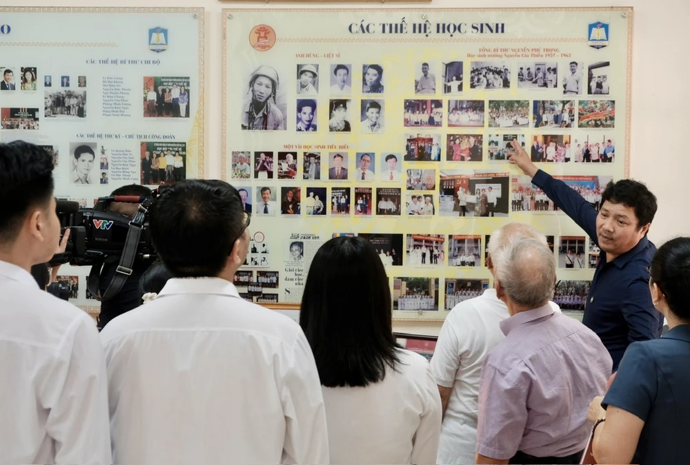 Hiệu trưởng Lê Trung Kiên tự hào giới thiệu, chia sẻ về những tấm ảnh của Tổng Bí thư Nguyễn Phú Trọng đang được lưu giữ tại phòng truyền thống của nhà trường. Ảnh: TT