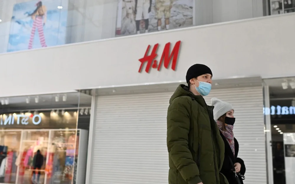 Cặp đôi đi ngang qua cửa hàng H&amp;M đã bị đóng cửa ở Nga. Ảnh: REUTERS