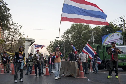 [Caption]Thai anti-government protesters hold national flags as they start massing at one of their designated sites in a move to 'shut down' Bangkok on January 12,