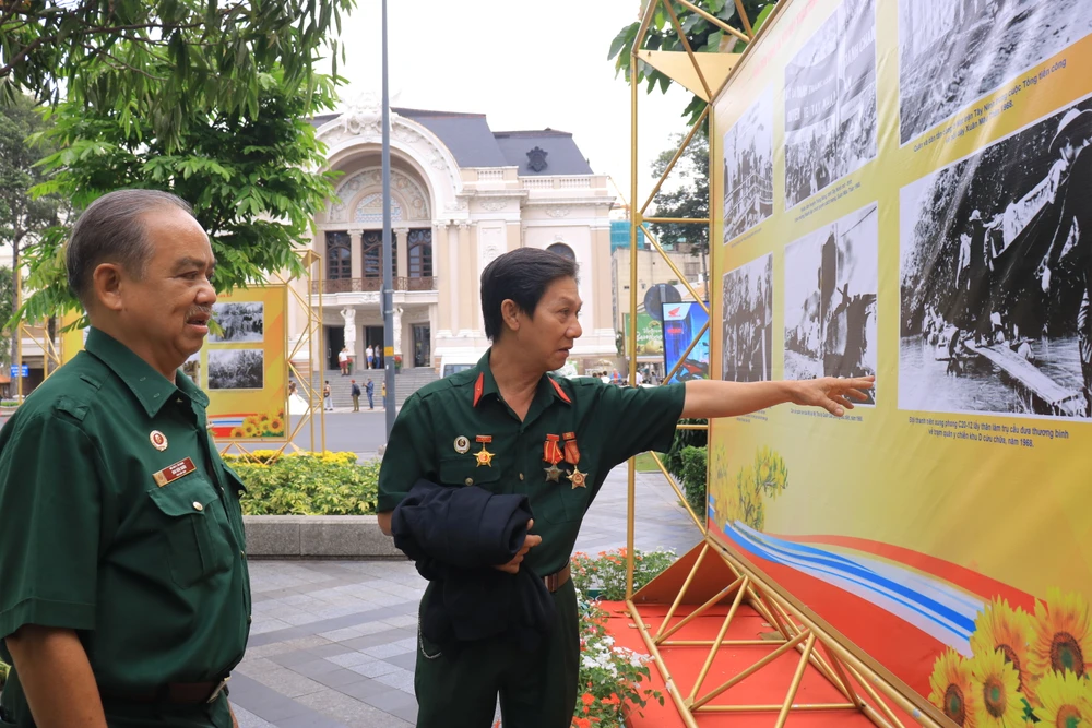 Cựu chiến binh Mai Văn Xuân (trái) cùng đồng đội xúc động nhìn những bức ảnh. Ảnh: VT