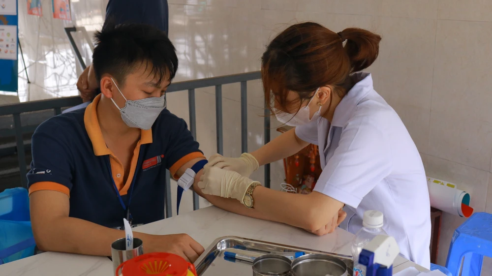 Nhân viên y tế thực hiện lấy máu xét nghiệm HIV cho công nhân Nhà máy Thời trang Phong phú: Ảnh: VT