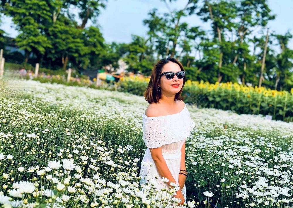 Chị Nguyễn Thị Thu Hương (TP Tam Kỳ) thích thú check-in bên vườn cúc mộng mơ. Ảnh: NVCC