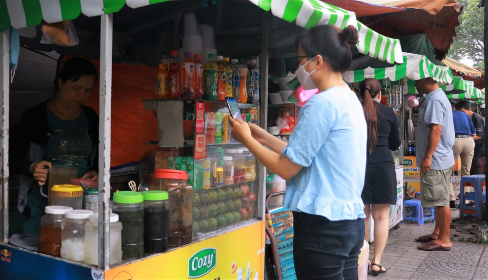 Khách hàng thực hiện thanh toán bằng mã QR sau khi mua nước tại quận 1. Ảnh: VÕ THƠ Khách hàng thực hiện thanh toán bằng mã QR sau khi mua nước tại quận 1. Ảnh: VÕ THƠ