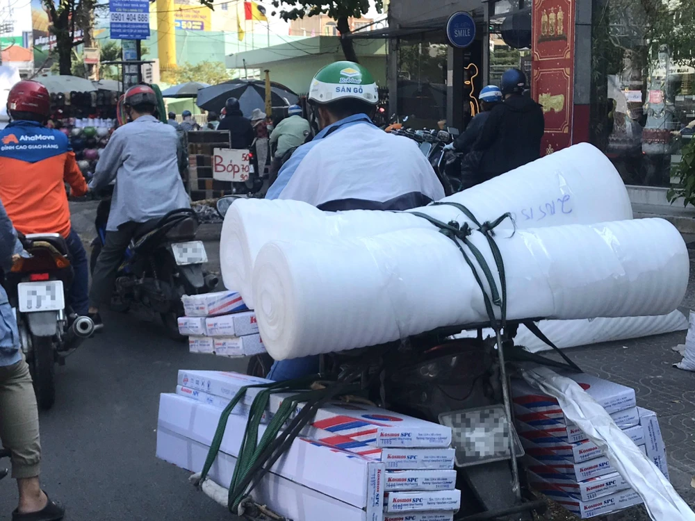 Một người đàn ông tận dụng những chỗ trống trên xe máy để treo hàng. Ảnh: THẢO HIỀN