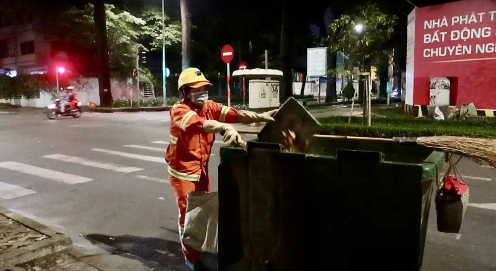 Chị Trúc, hiện đang là công nhân môi trường quận 3, đang miệt mài với công việc của mình giữa thời tiết oi bức của đêm. Ảnh: THẢO HIỀN