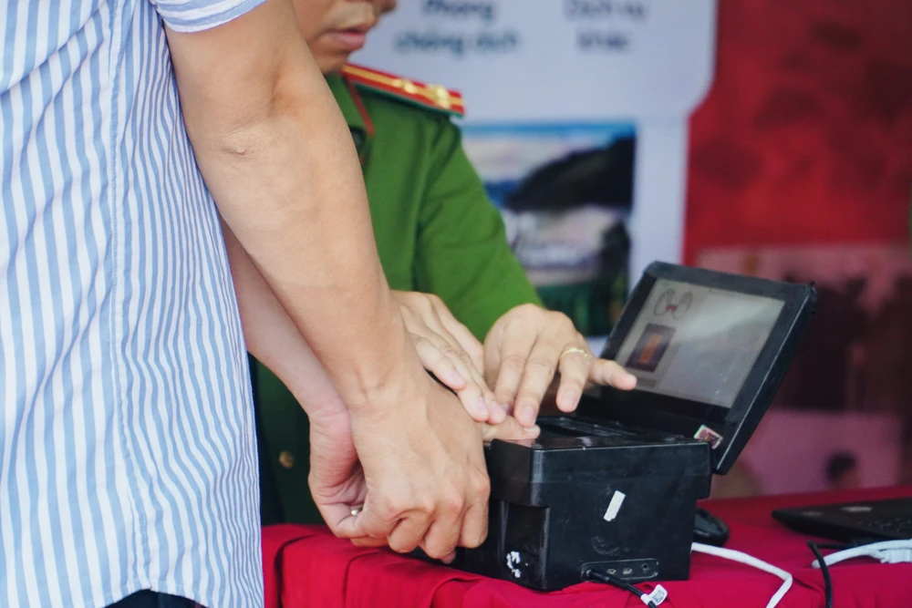 Sau khi khai báo thông tin, người dân được chụp hình và lăn dấu vân tay. Ảnh: HUỲNH THƠ