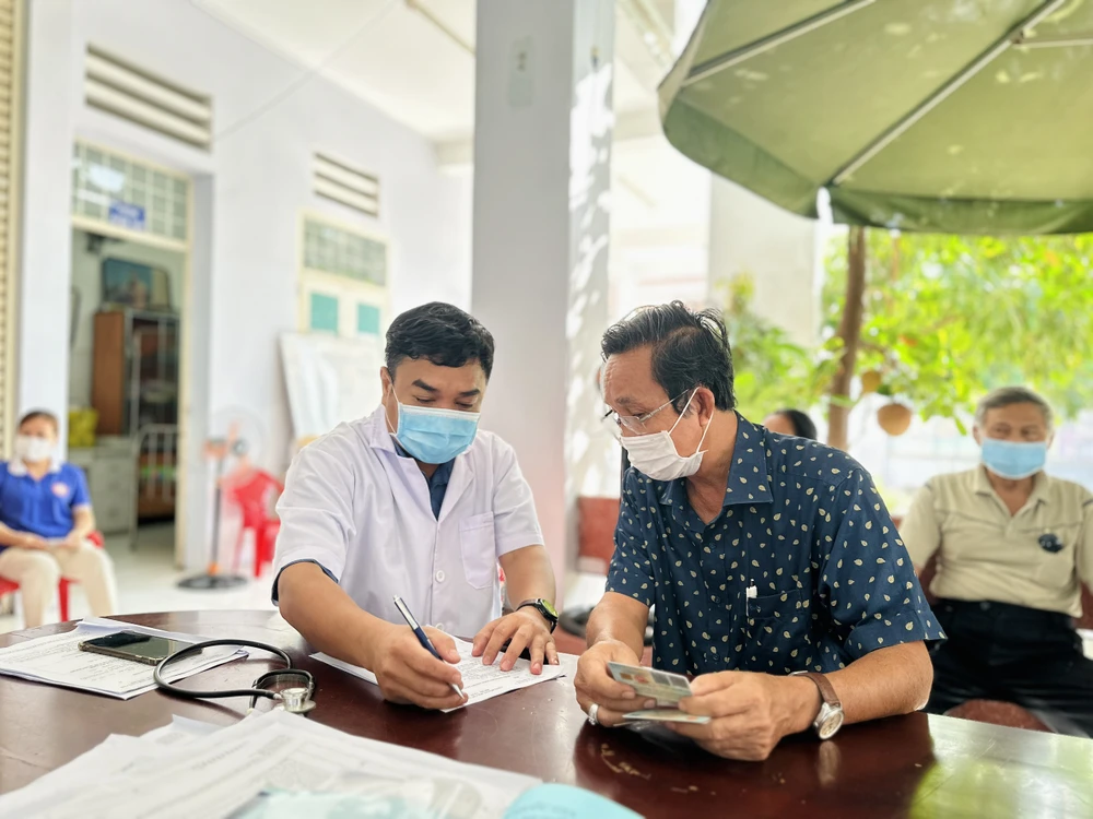 BS Phạm Cung, Trưởng trạm Y tế phường Tân Hưng Thuận, quận 12 đang khám sàng lọc sức khỏe cho người cao tuổi. Ảnh: TRẦN MINH