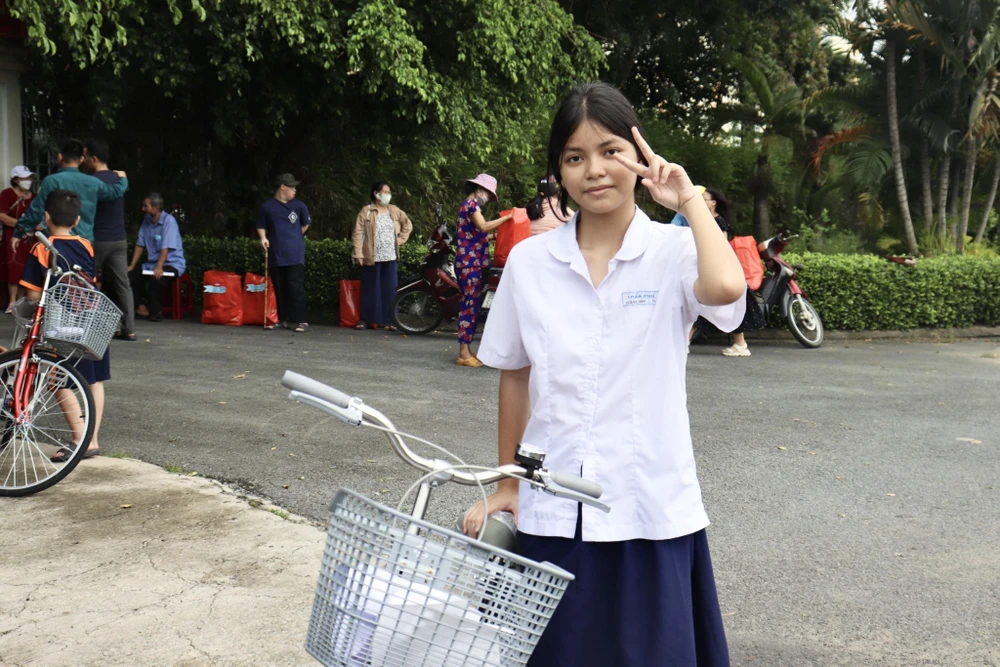 Em Liêu Hoàng Anh, học sinh giỏi 7 năm liền, tạo dáng vui mừng khi nhận được học bổng và xe đạp mới. Ảnh: TRẦN MINH
