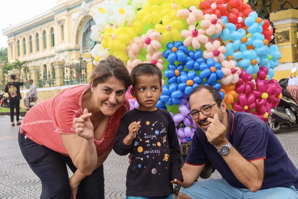 Gia đình chị Maria và chồng Enrique đến từ Barcelona chia sẻ, chị đến với Việt Nam để du lịch. Thấy tại trung tâm TP.HCM có nhiều người dân lại chụp hình những xe hoa và bong bóng nên thấy rất ngạc nhiên. Chị có hỏi thử vài người dân nơi đây thì được biết đây là những xe hoa mang hơi hướng mùa thu Hà Nội, tôi thấy rất vui. Sẵn tiện đây tôi và chồng sẽ làm một chuyến du lịch tại Hà Nội. Ảnh: TRẦN MINH