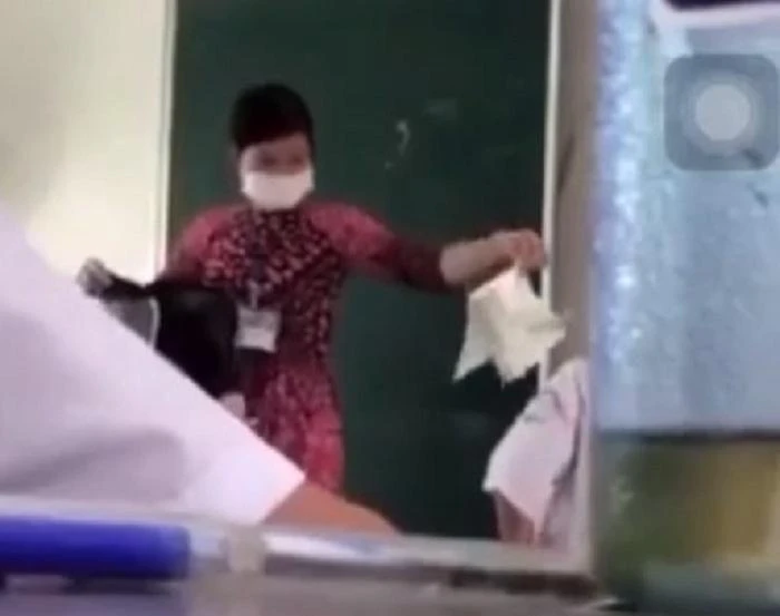 Cô giáo thả sách vở học sinh xuống nền lớp. Ảnh cắt từ Clip.