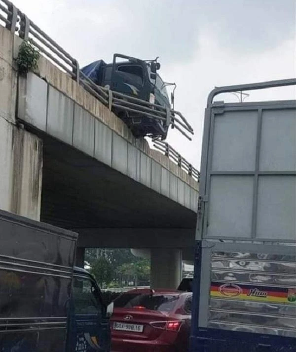 Đầu chiếc xe tải nhô ra khỏi lan can cầu vượt khiến nhiều người đi đường kinh hãi. Ảnh: AX