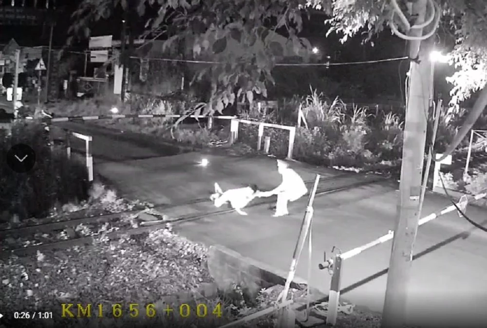 Hình ảnh nhân viên gác chắn kéo người đàn ông khỏi đường ray xe lửa khi tàu vừa tới. Ảnh: Cắt từ clip.