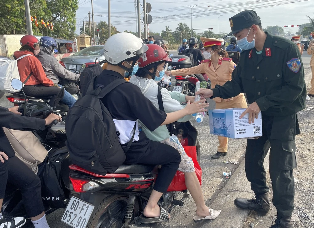 Lực lượng công an phát nước suối cho người dân về quê đón Tết Nguyên đán 2023. Ảnh: VH.