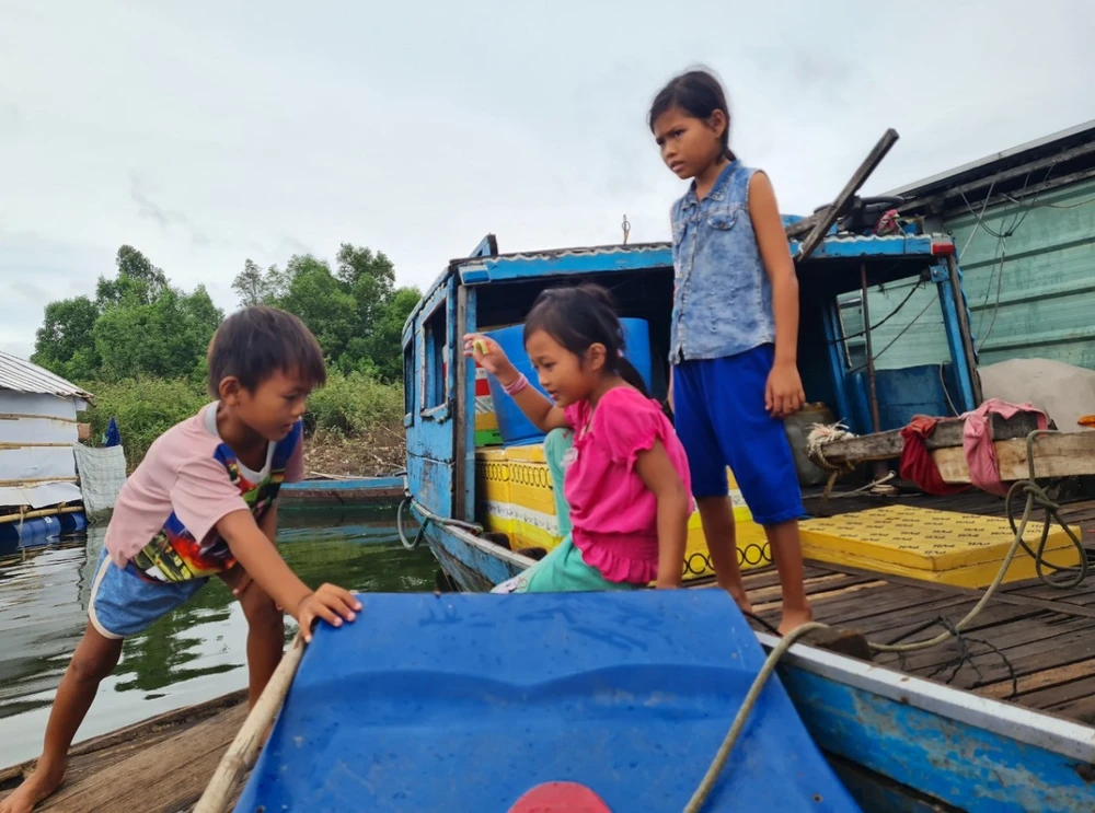 Những đứa trẻ lấy xuồng đi qua các nhà bè để chơi.
