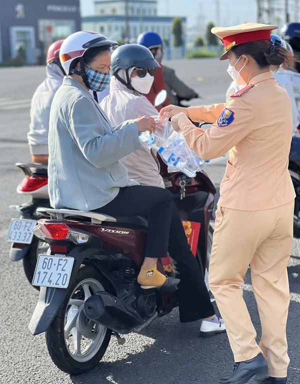 Người dân nhận nước suối mát từ một chiến sĩ CSGT Công an tỉnh Đồng Nai. Ảnh: VH.
