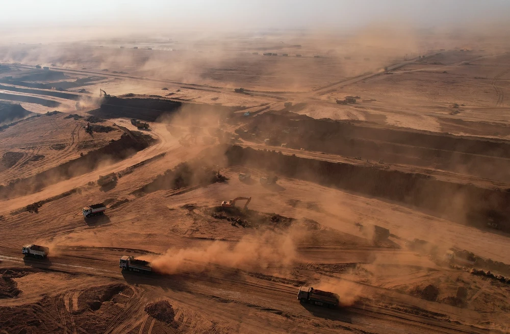 Bụi bay theo gió khi những chiếc xe ben di chuyển trên công trường.