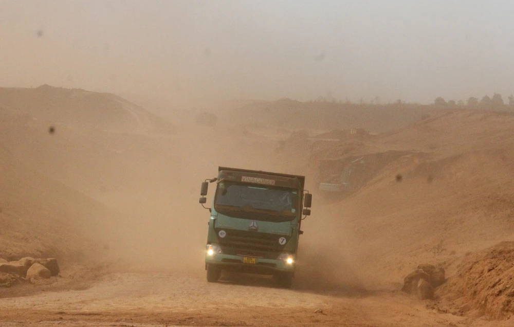 Những chiếc xe ben chở đất đi trong công trình bụi bay dầy đặc khiến một số tài xế phải bật đèn sương mù để cảnh báo.