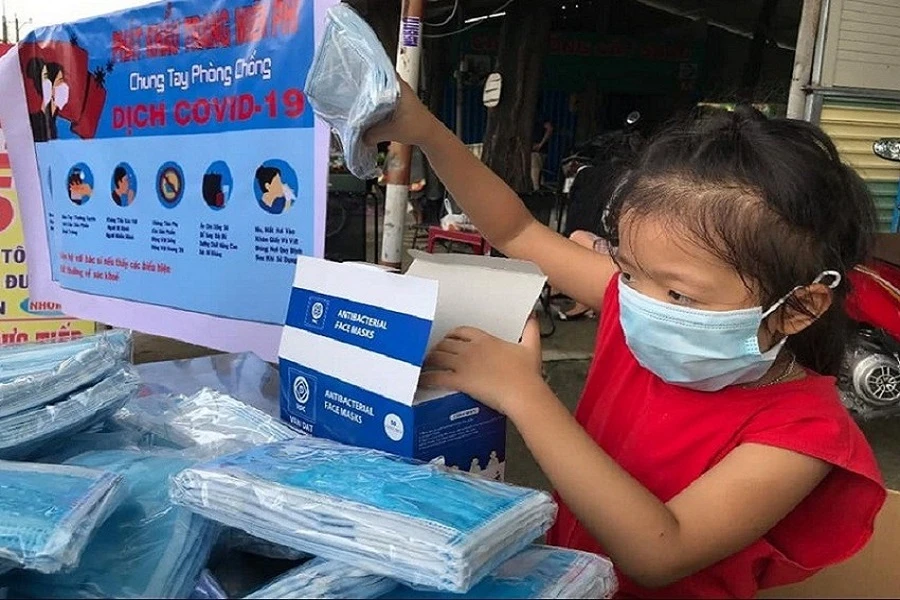 Một bé gái phát khẩu trang miễn phí cho người dân ở TP Biên Hòa trong đợt dịch Covid-19 vừa qua. Ảnh: VH.
