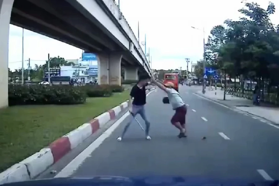 Tài xế taxi dùng gậy 3 khúc đánh nhau với người đi xe máy dùng mũ bảo hiểm. Ảnh: Cắt từ clip.