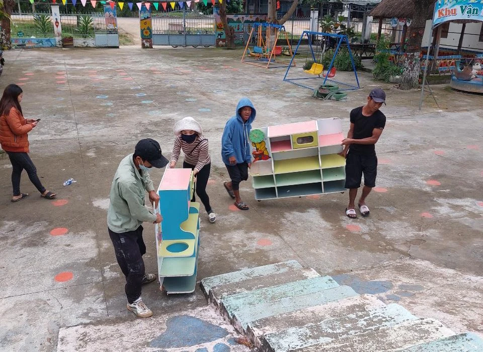 Vận chuyển bàn ghế học sinh vào nơi an toàn. Ảnh: LX