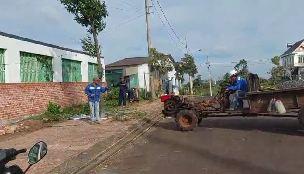 Người và phương tiện phá dỡ bờ tường chắn trước nhà dân. Ảnh: VQ