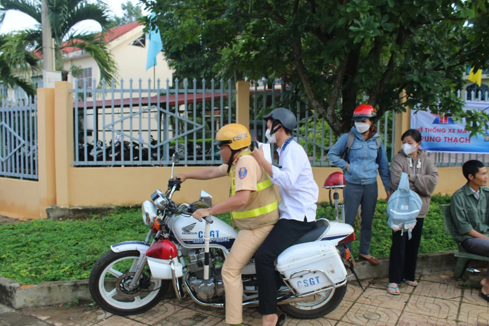 Đại úy Lê Ngọc Cao Sang chở nam sinh đến điểm làm thủ tục dự thi. Ảnh: HD