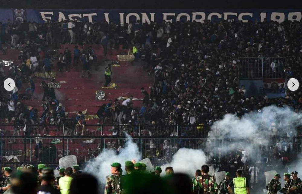 Trên khán đài thì lửa cháy, dưới sân thì... hỗn loạn. Ảnh: AFP Cảnh sát dùng súng bắn hơi cay để ngăn chặn đám đông. Ảnh: AFP