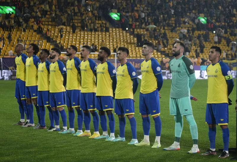 Ronaldo ngồi xem đồng đội ra sân tiếp Al Taj. Lẽ ra vòng 12 giải Saudi Arabia diễn ra giữa tuần này, song do thời tiết mưa quá kinh khủng, hệ thống điện của sân lại gặp vấn đề nên trận đấu dời lại vào thứ sáu, đó là vòng đấu Al Nassr tiếp Al Taj Fan đến xem Ronaldo, tuy nhiên siêu sao của đội chưa thể ra sân được do án phạt treo giò 2 trận ở Anh cũng có hiệu lực tại giải Saudi Arabia. Tuy nhiên Al Nassr cũng thắng 2-0 và có 29 điểm dẫn đầu bảng xếp hạng sau 12 vòng. Ronaldo ngồi trên khu VIP của sân với các lãnh đạo Al Nassr. Một fan nữ tiến đến xin chụp hình chung với Ronaldo. ...OK, chụp nhé. Cho đến nay, áo chính hãng của Ronaldo đã bán được 50 ngàn chiếc. Ronaldo quan sát sân Mrsool qua cửa kính. Ronaldo chào fan khi hiện diện trên khu VIP.