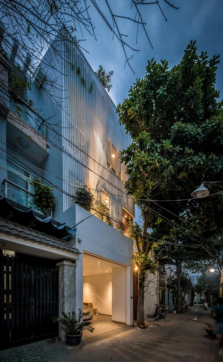 Mặt tiền nhà nằm hướng tây nên kiến trúc sư sử dụng một hệ lam sắt sơn trắng tạo cảm giác nhẹ nhàng và cây xanh để giảm lượng nắng vào nhà.