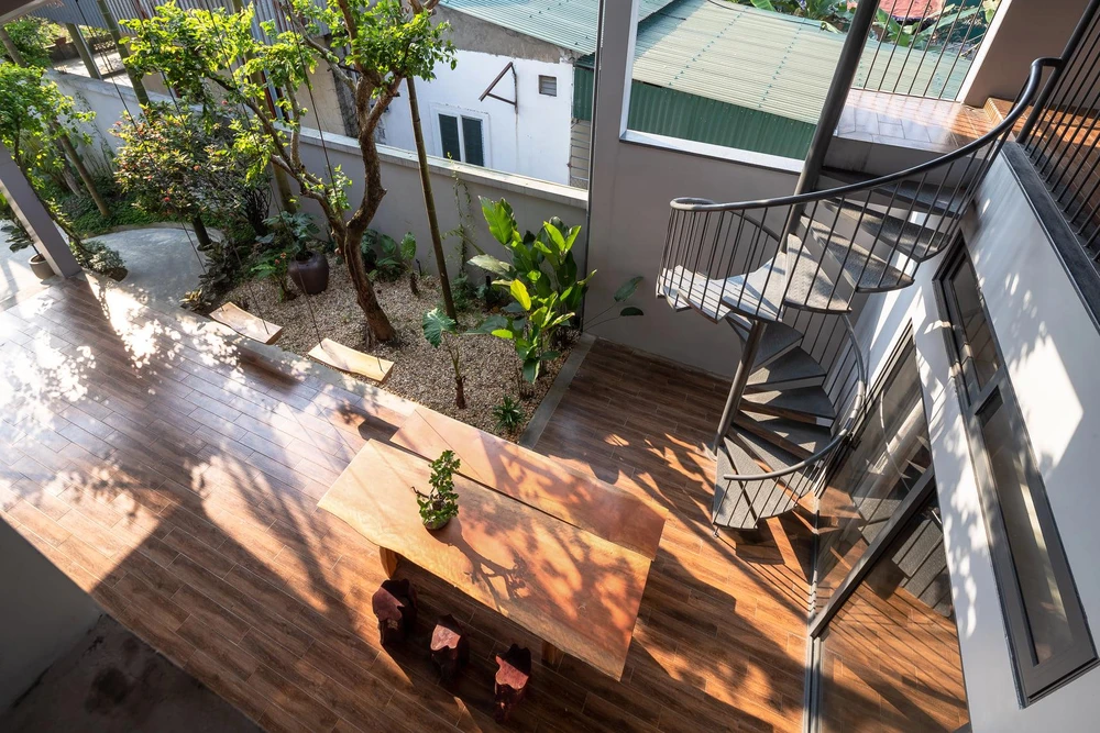 Kiến trúc sư thiết kế khoảng trống rộng rãi có bộ bàn gỗ dài kết hợp với cây xanh dọc hành lang tạo nên sân chơi lý tưởng cho gia đình.