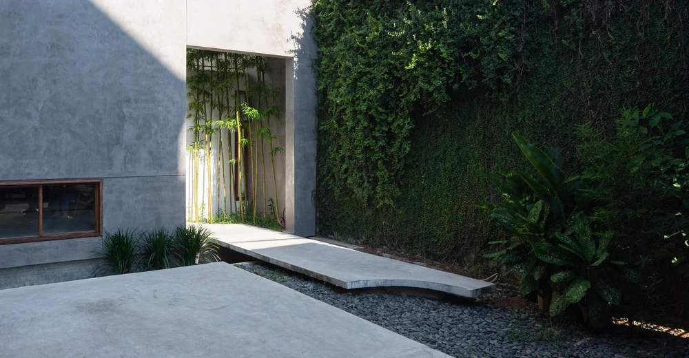 Sân thứ nhất được bố trí theo lối thông thường một góc 90 độ. Nhóm thiết kế đặt cửa chính vừa kín đáo, tinh tế, vừa tránh được ánh nắng trực tiếp của hướng tây.