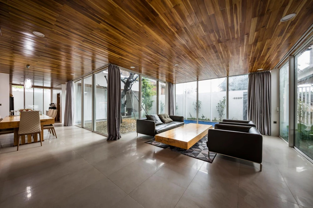 Phòng khách và bếp thiết kế gần nhau, hai không gian này đều hướng ra khoảng cây xanh bên ngoài giúp không gian sống trở nên thú vị hơn.